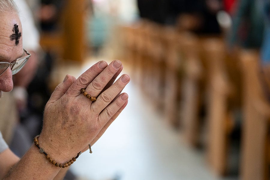 man prays the rosary during Mass